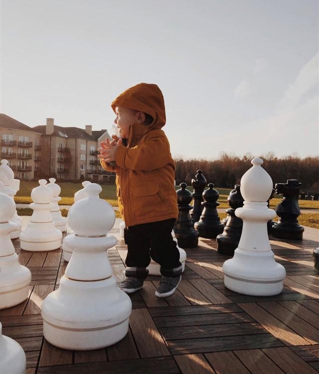 little boy playing on outdoor chess set