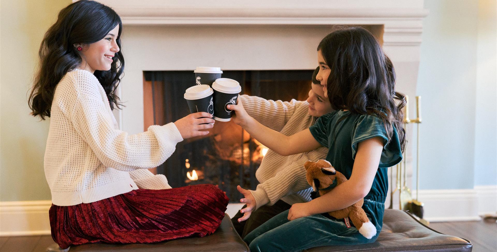 Siblings sharing hot cocoa at Christmas time